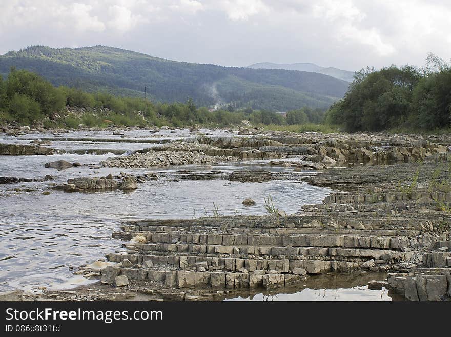 The mountain river flowing on stones with mountains on a background