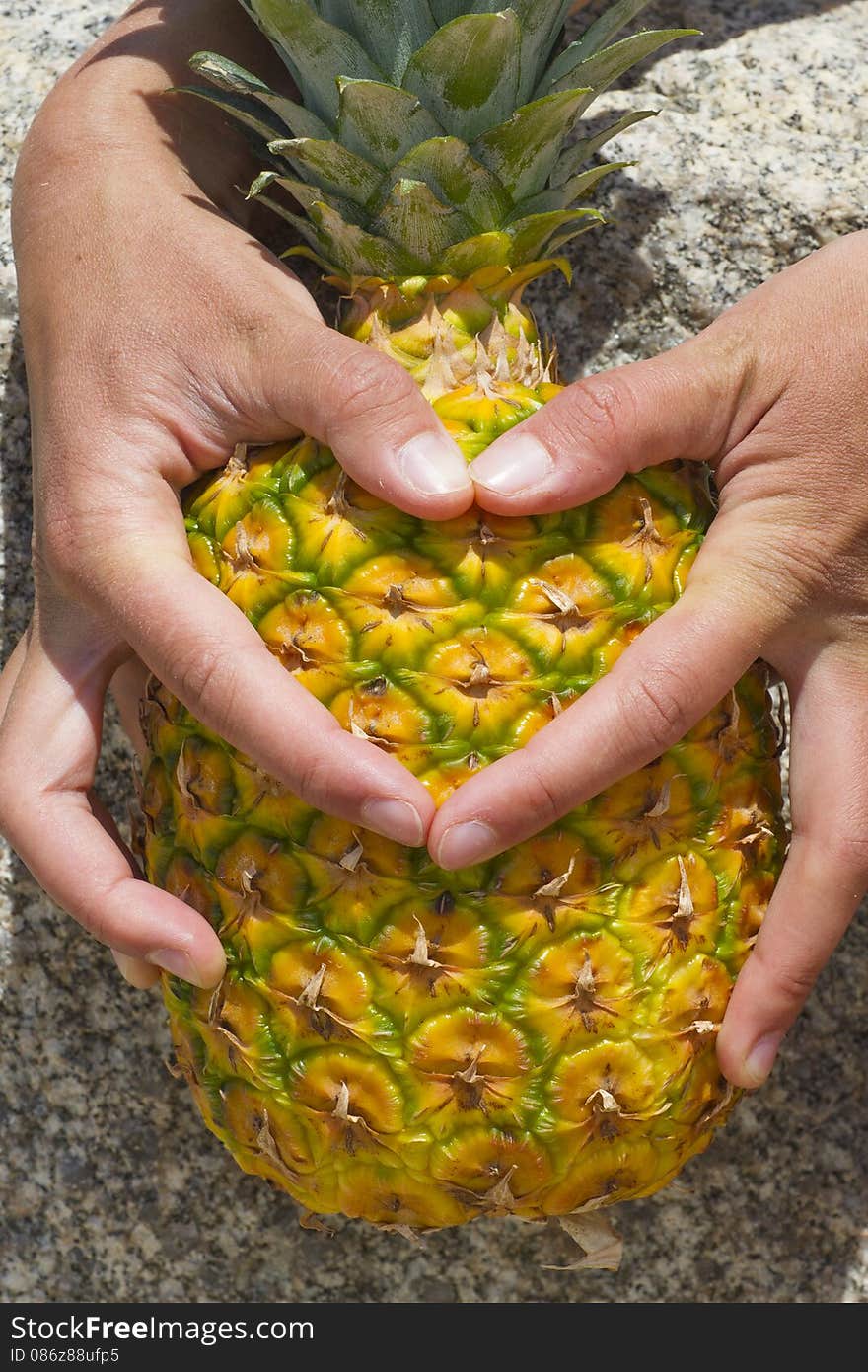 Thumbs form a heart on the pineapple