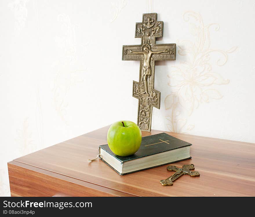 Holy bible with green apple and two crosses on the brown wooden table