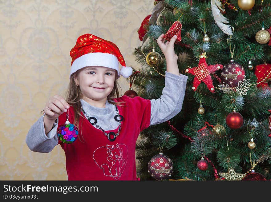 Little Girl In Santa Hat Near Christmas Tree