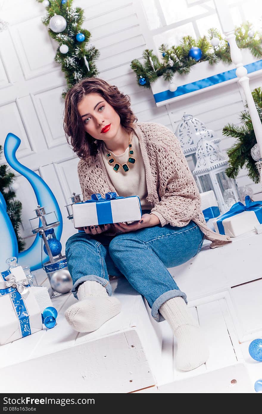 Pretty young girl in jeans and a cardigan with Christmas gifts c