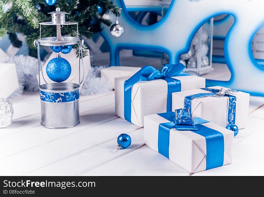 White Christmas gifts with blue ribbon on white wooden floor. White Christmas gifts with blue ribbon on white wooden floor