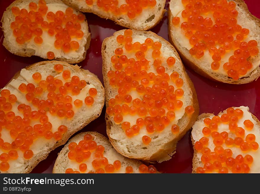 Bread and butter with red selmon caviar on a red plate. Bread and butter with red selmon caviar on a red plate.