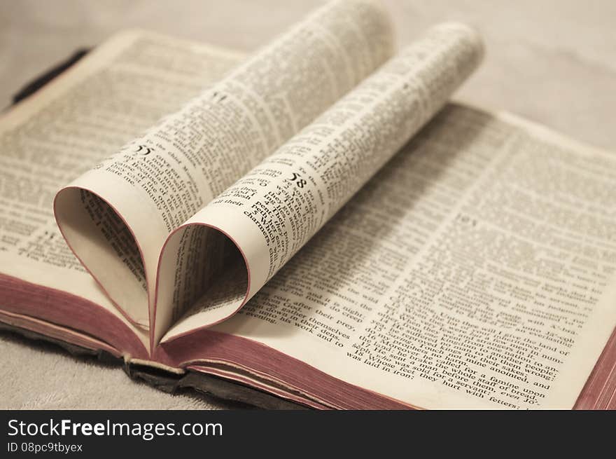 Close up of the bible with the pages folded in to form a heart shape with the pages of the book. Close up of the bible with the pages folded in to form a heart shape with the pages of the book.