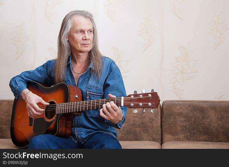 Middle-aged man playing guitar at home