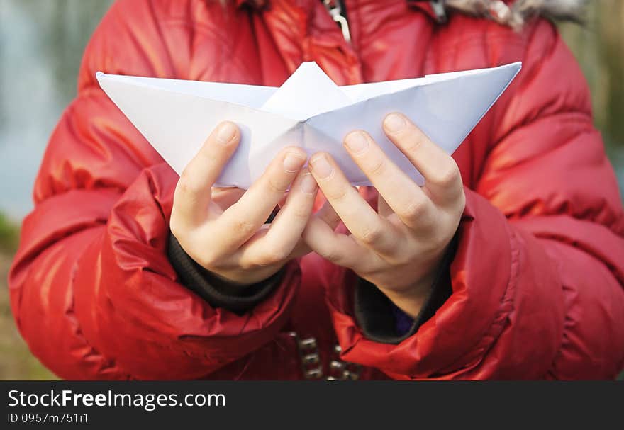 Hands holding a paper boat closeup outside