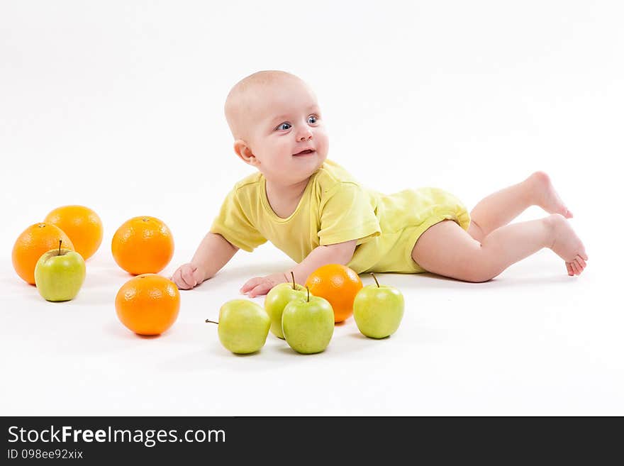 Cute surprised baby looks at green apple on a white background