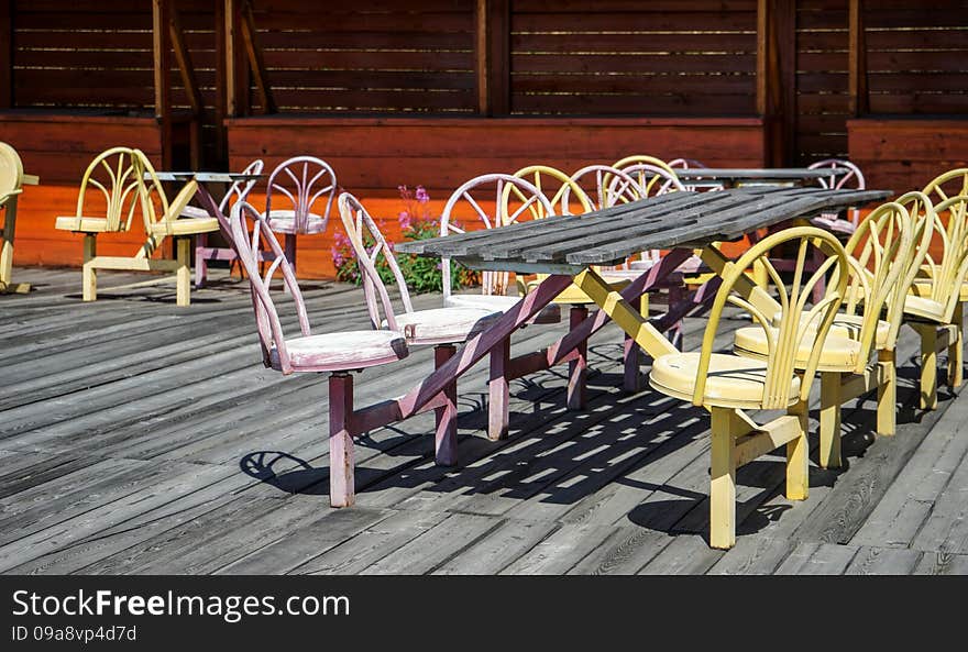 Empty street cafe with old colored metal chairs and wooden floor