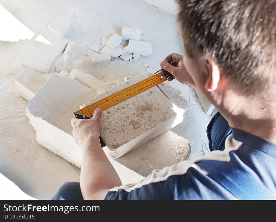 Middle-aged man worker measures the ruler silicate brick closeup