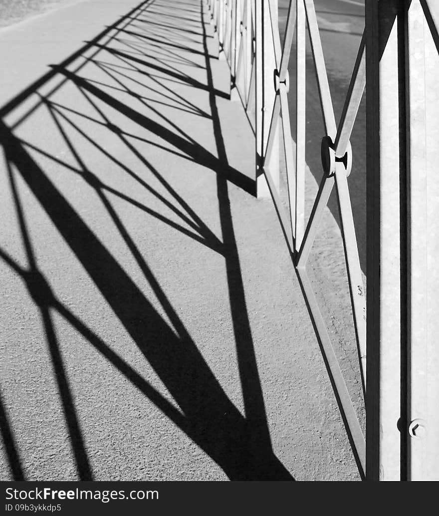 Geometric pattern with shadow of the metal fence outside black and white