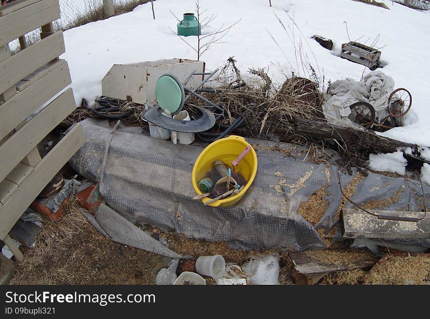 Yellow plastic basin of water, brushes and rusty paint roller on backyard. Mess on backyard.