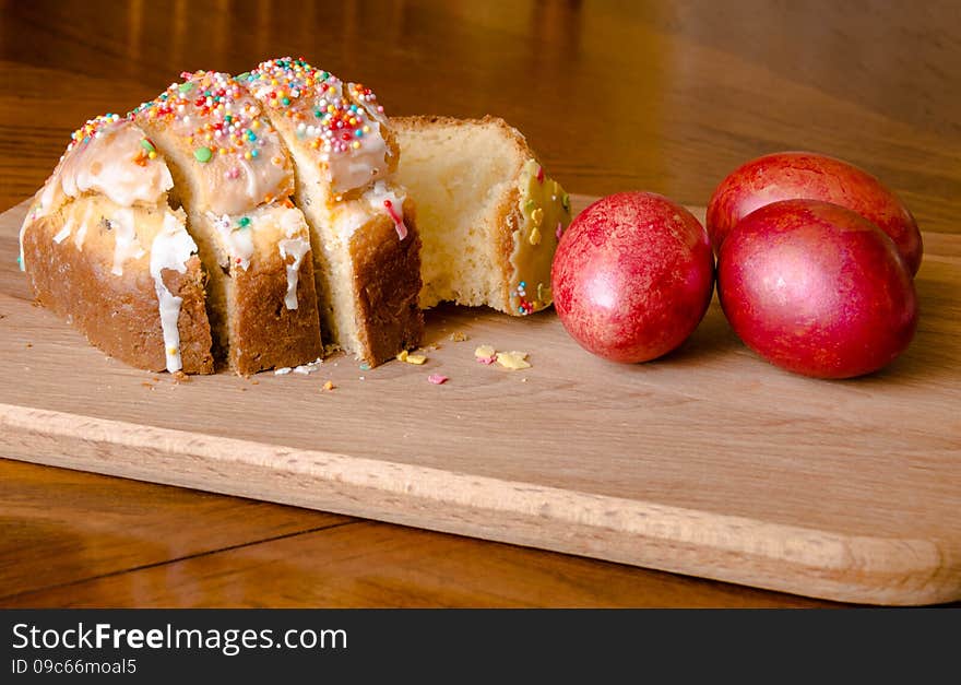 Easter cake and red eggs on a wooden board