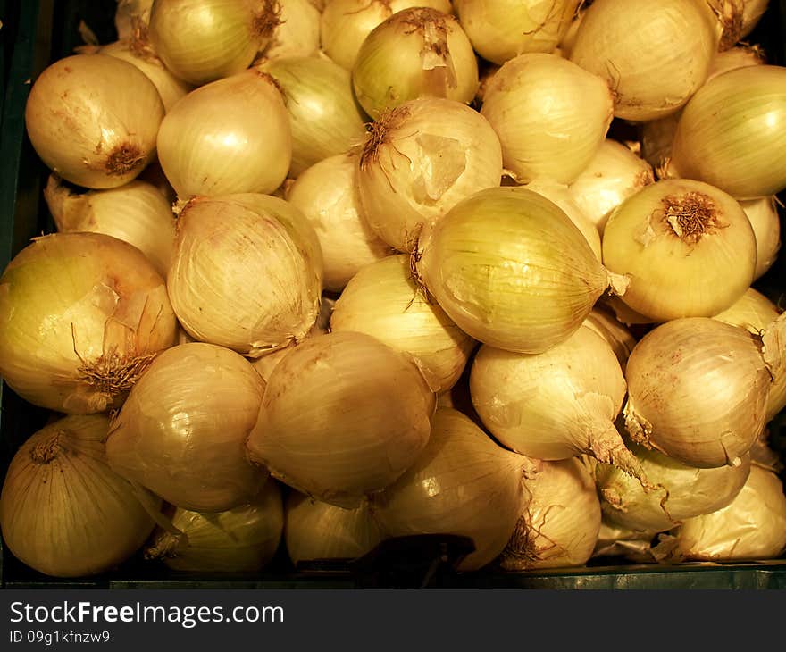 Raw ripe white onions pile on display in a market