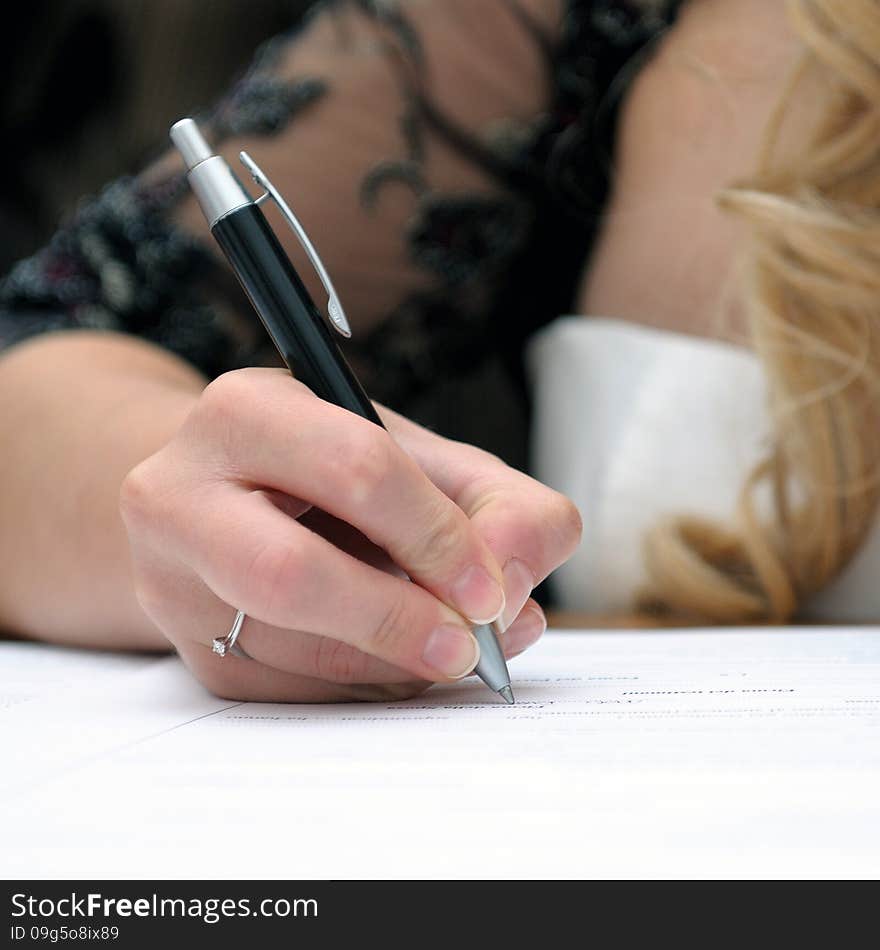 Bride signing the marriage certificate after the wedding. Bride signing the marriage certificate after the wedding