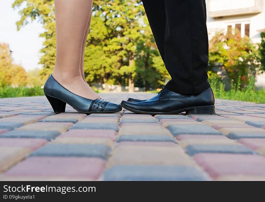 Feet of men and women standing on the sidewalk of the color tiles closeup. Feet of men and women standing on the sidewalk of the color tiles closeup