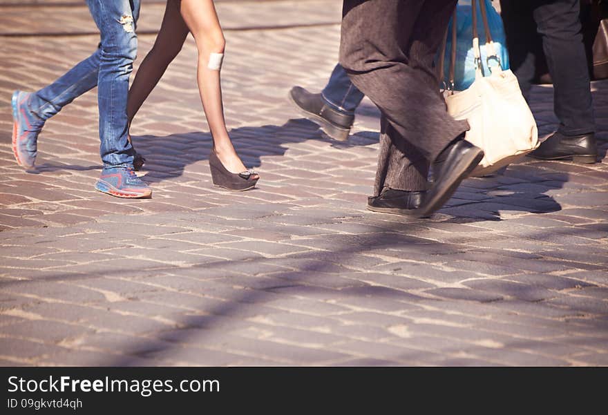 Feet of male and female pedestrians in a crosswalk in the city center on sunny spring day. Feet of male and female pedestrians in a crosswalk in the city center on sunny spring day