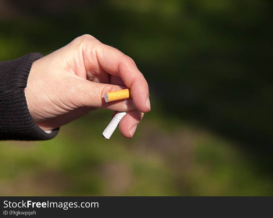 Female hand breaks a cigarette closeup outside