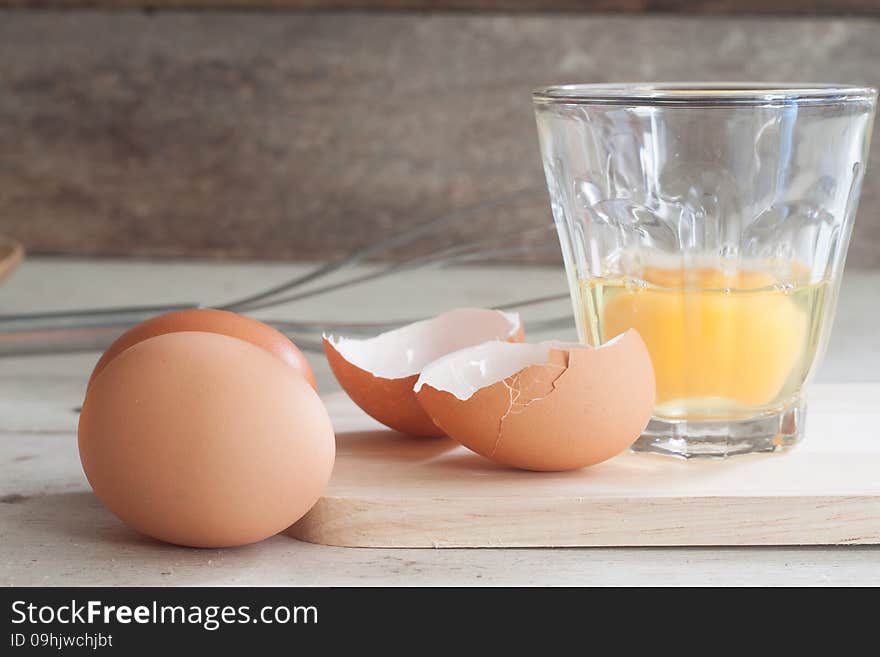 Ingredients and tools to make a cake, eggs, bakery cups on wood table