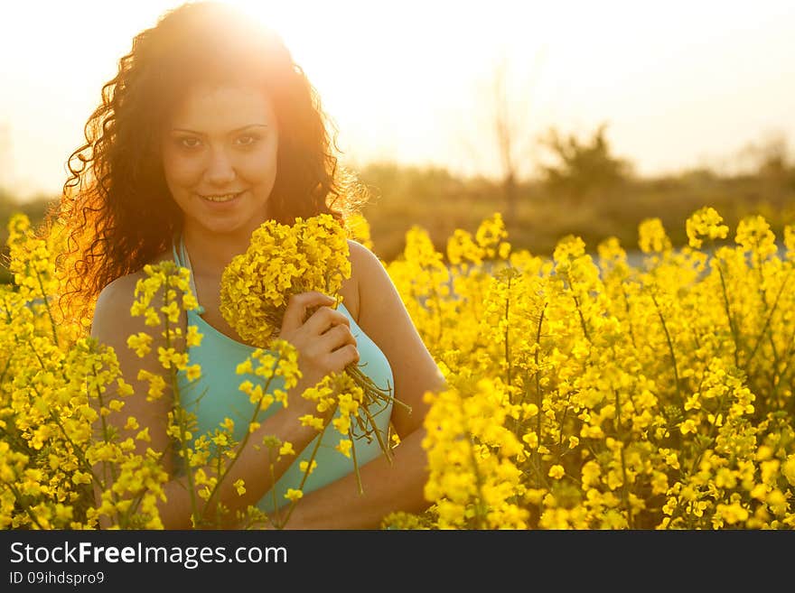 Beautiful happy woman in canola field in sunny day