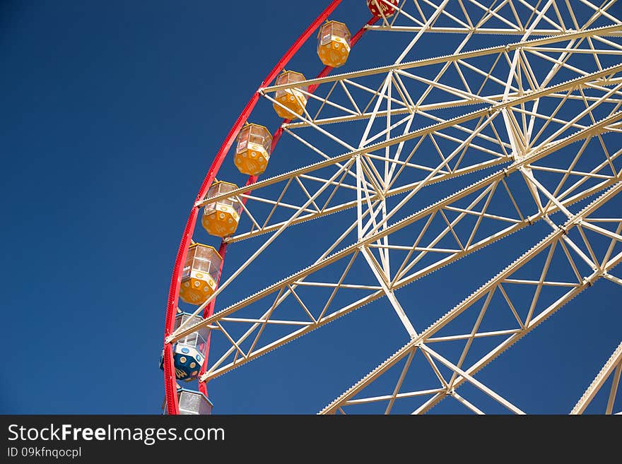 Atraktsion Ferris wheel against a blue sky with clouds. Atraktsion Ferris wheel against a blue sky with clouds