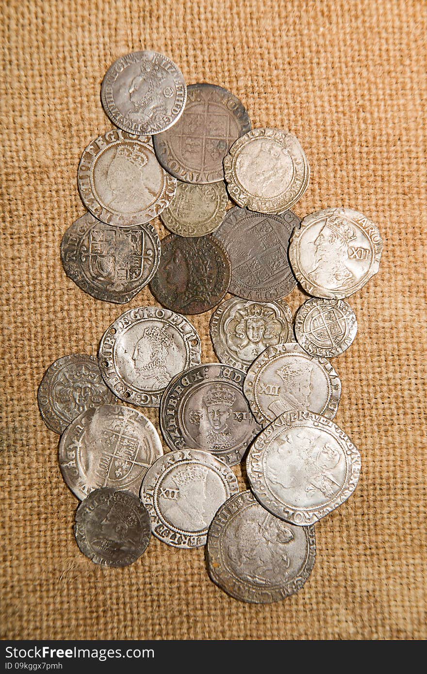 Ancient silver coins with portraits of kings on the old cloth