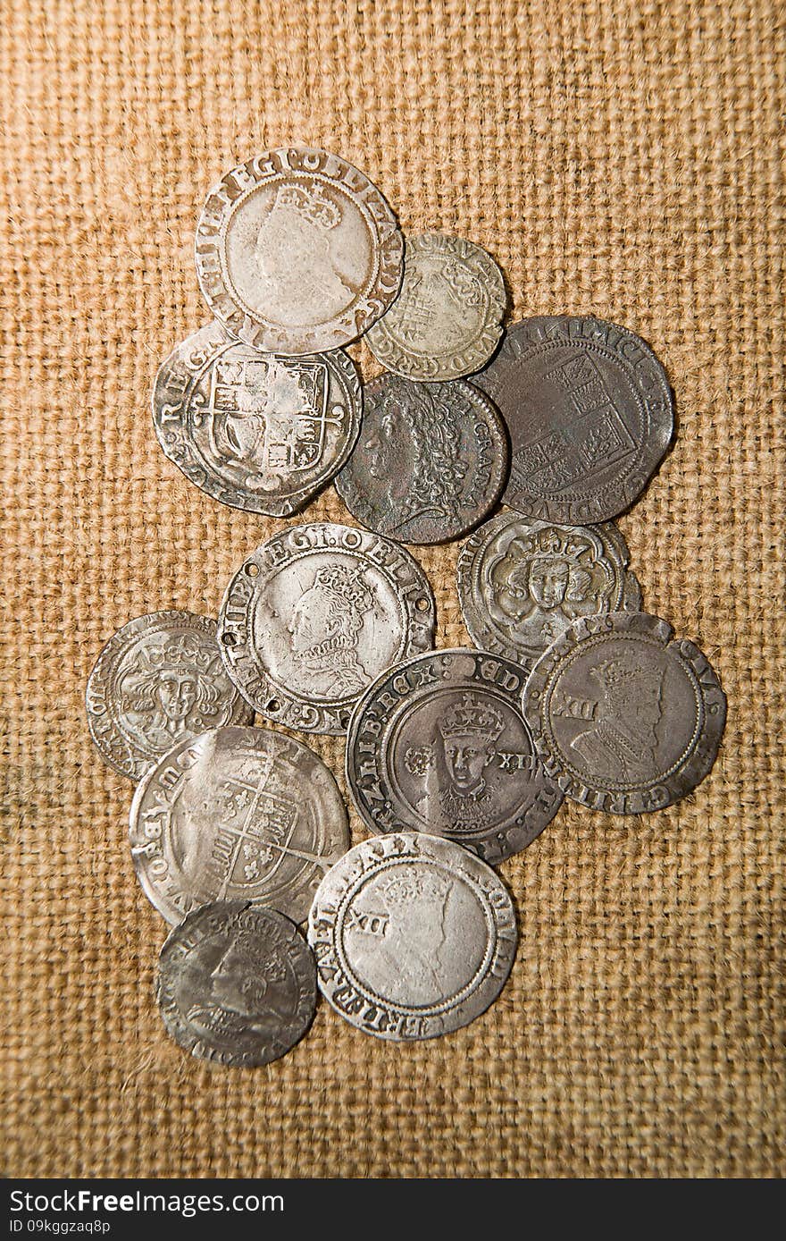 Ancient silver coins with portraits of kings on the old cloth