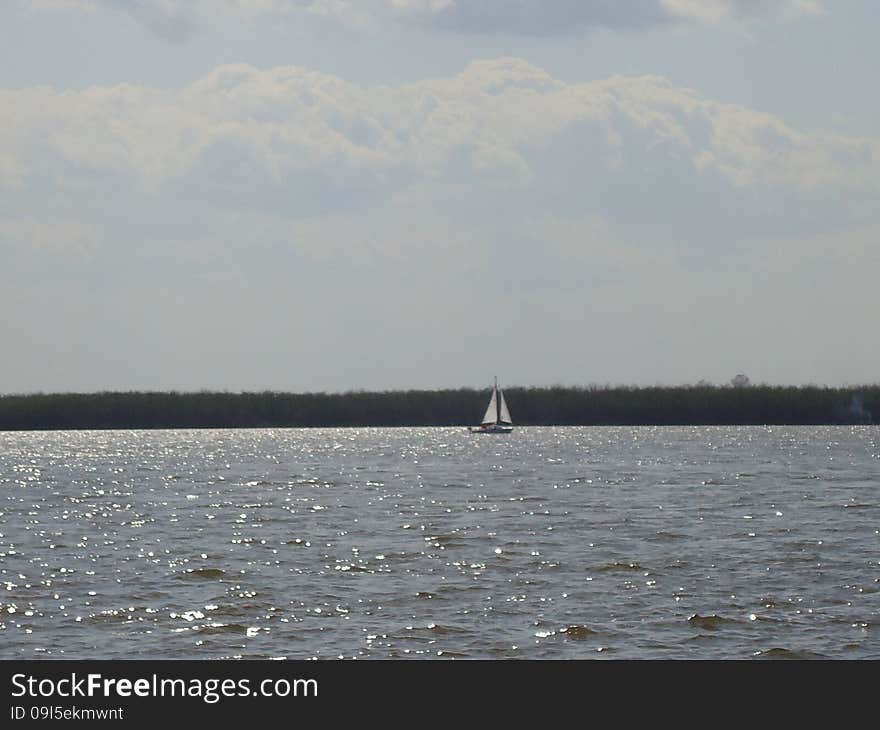 Sailboat floats alone on vast expanses of the river. Sailboat floats alone on vast expanses of the river.