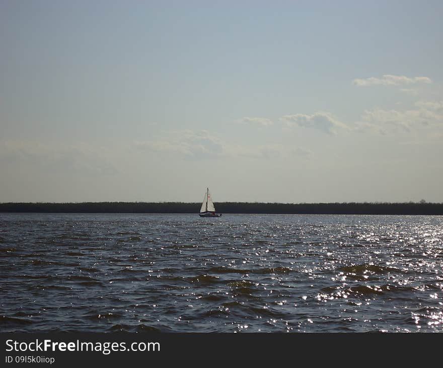 Sailboat floats alone on vast expanses of the river. Sailboat floats alone on vast expanses of the river.