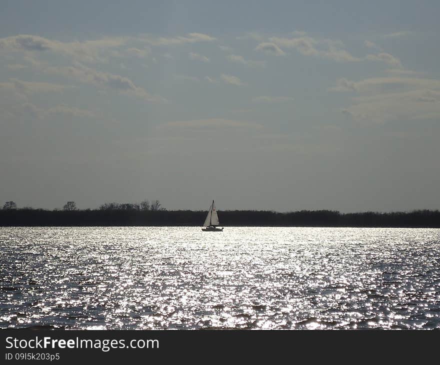 Sailboat floats alone on vast expanses of the river. Sailboat floats alone on vast expanses of the river.