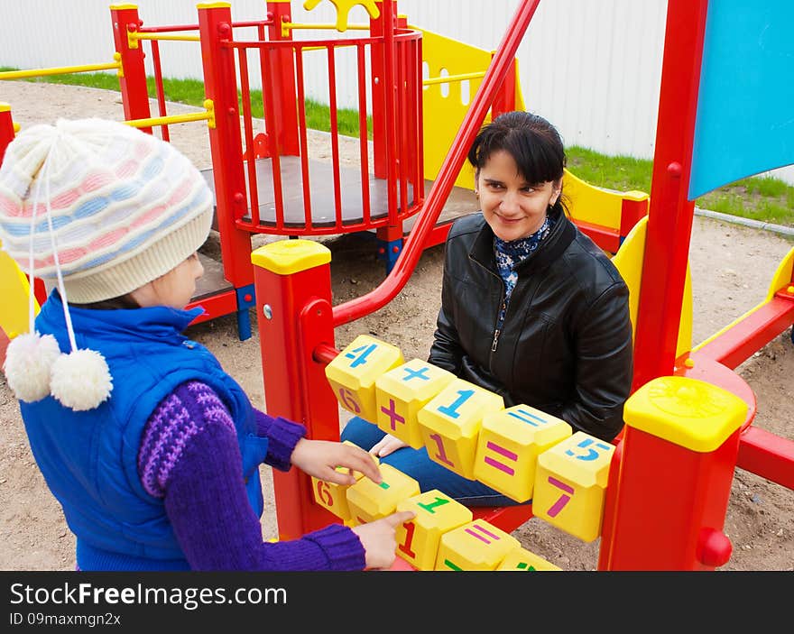 Mother watching her daughter, counting on the dice on the playground