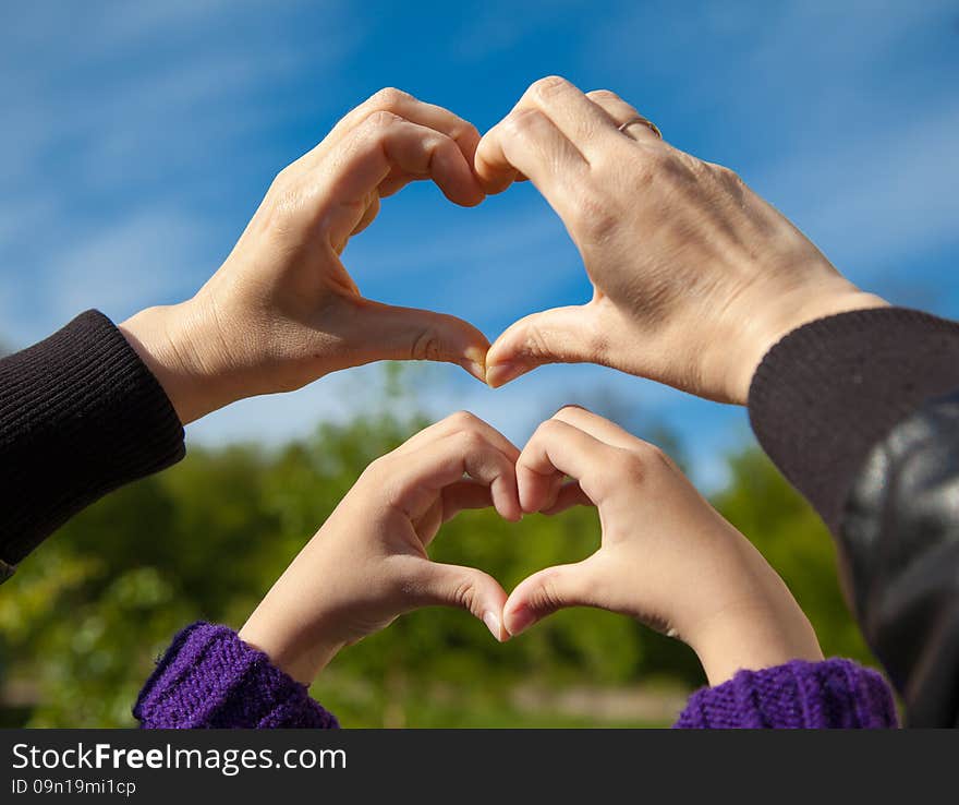 Girl and her mother show sign of heart with their hands