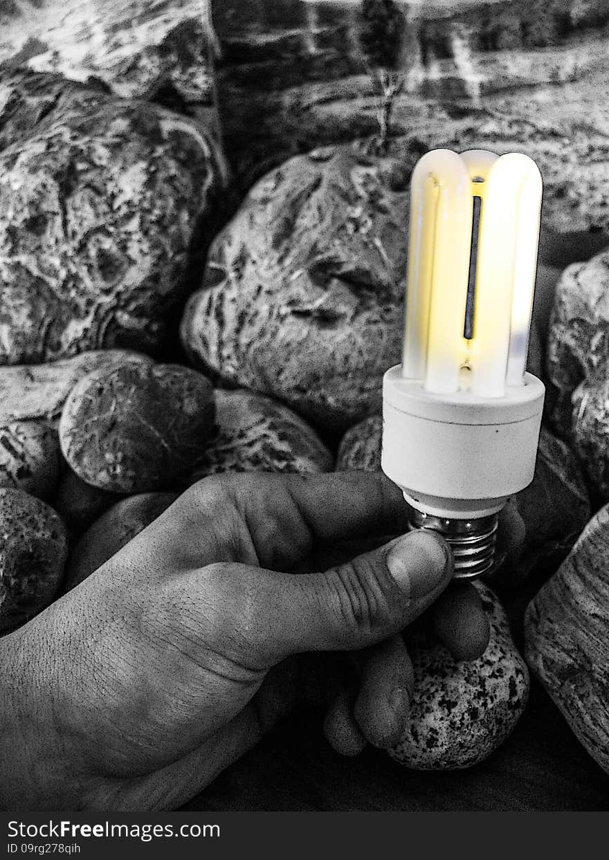 Abstract photography - concept that energy is hidden in live, you can make light with your hands. A creative black and white photograph with a striking contrast. The image shows a hand holding a glowing lightbulb against a textured stone background. The light stands out in warm yellow tones, offering a stark contrast to the monochrome surroundings. Abstract photography - concept that energy is hidden in live, you can make light with your hands. A creative black and white photograph with a striking contrast. The image shows a hand holding a glowing lightbulb against a textured stone background. The light stands out in warm yellow tones, offering a stark contrast to the monochrome surroundings.