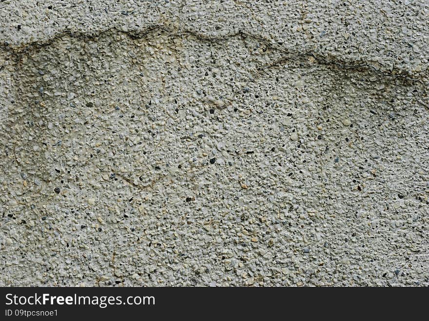 Frontal view of a weathered concrete wall with a horizontal crack. The aggregate are exposed and the material surface is rough. Frontal view of a weathered concrete wall with a horizontal crack. The aggregate are exposed and the material surface is rough.