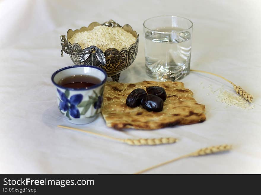 Iftar glass of water and black dates and cup on tea plus wheat and rice. Iftar glass of water and black dates and cup on tea plus wheat and rice