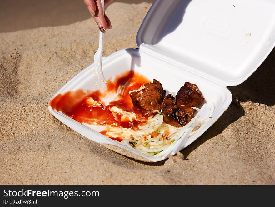 Female hand with a fork is taking a slice kebab