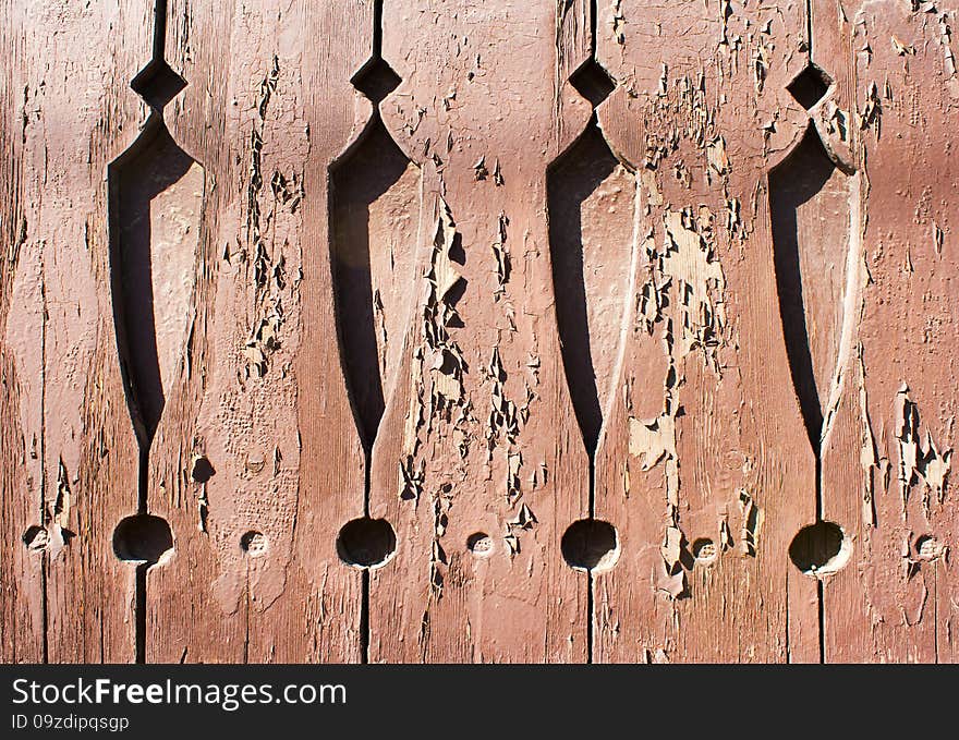 Old brown painted boards with cracked paint and carved patterns outside closeup. Old brown painted boards with cracked paint and carved patterns outside closeup