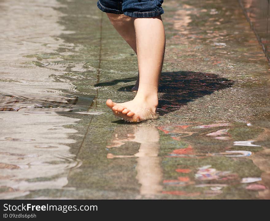 Boy's feet playing the fountain closeup on summer day. Boy's feet playing the fountain closeup on summer day