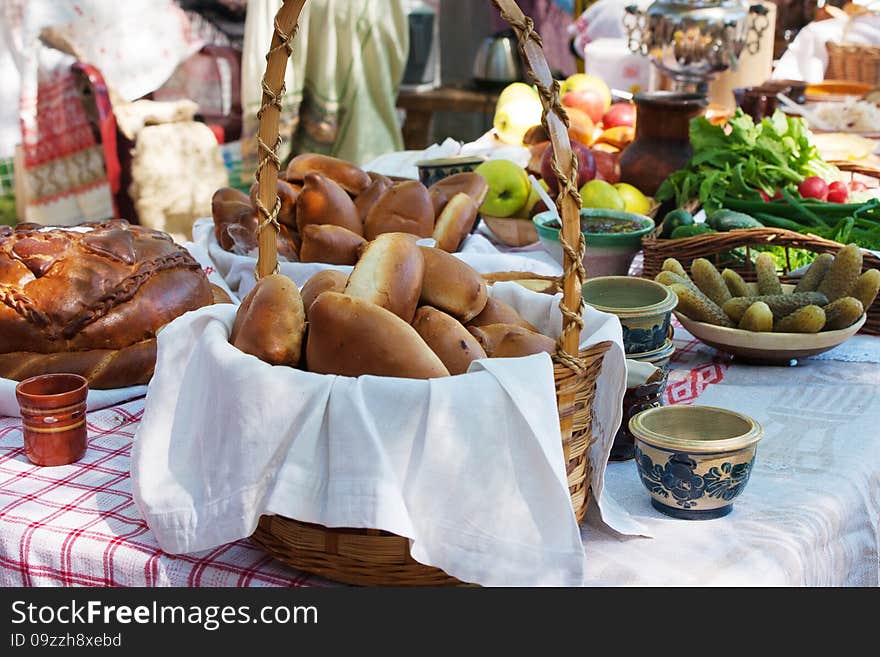 Cakes, bread, cucumbers, radishes and apples on a table in the city park outside. Cakes, bread, cucumbers, radishes and apples on a table in the city park outside