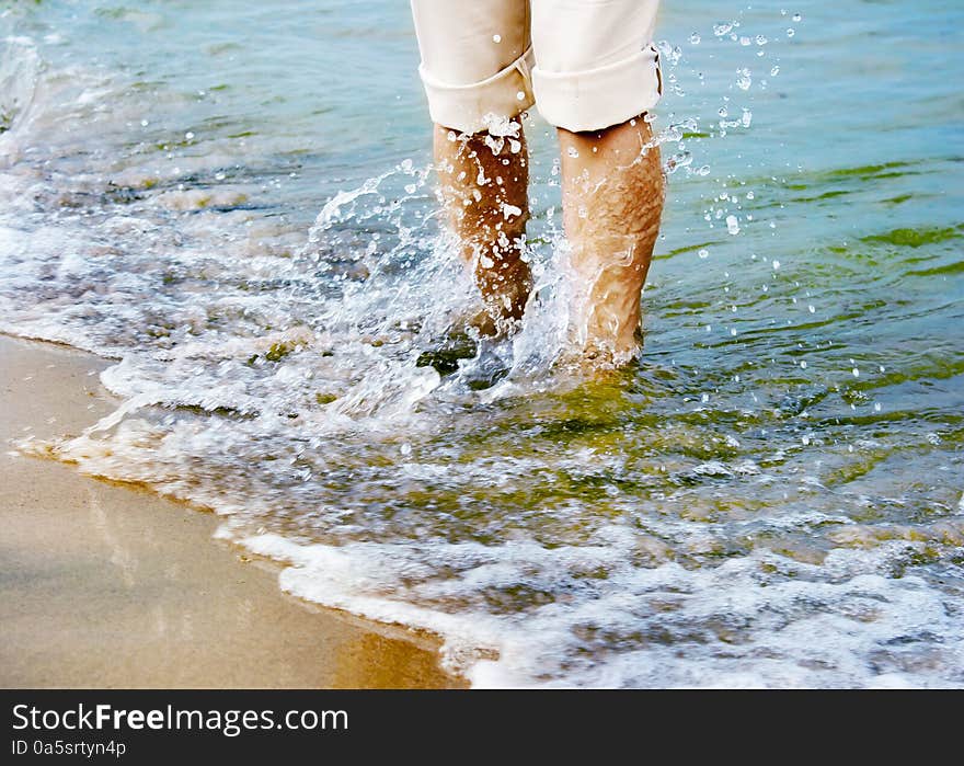 Female legs sweeping sea wave. close-up. Female legs sweeping sea wave. close-up