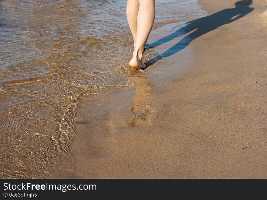 Barefoot woman walking on the sea shore on summer closeup. Barefoot woman walking on the sea shore on summer closeup