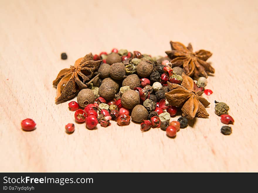 A mixture of grains of pepper and star anise on a wooden surface