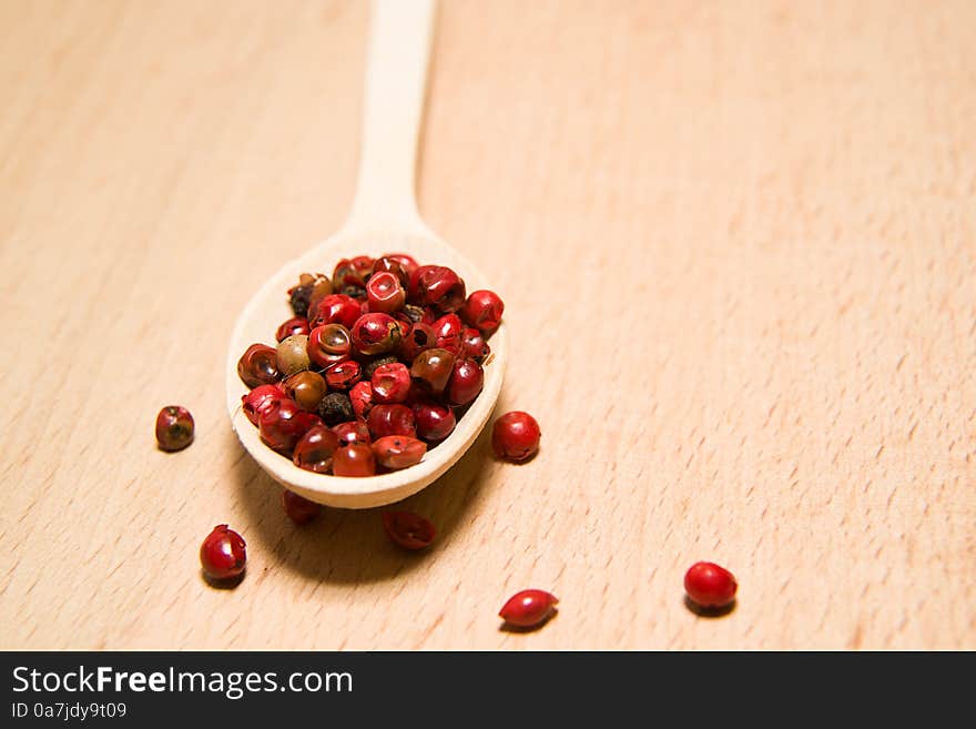 Spoon filled with a mixture of grains of pepper and star anise o