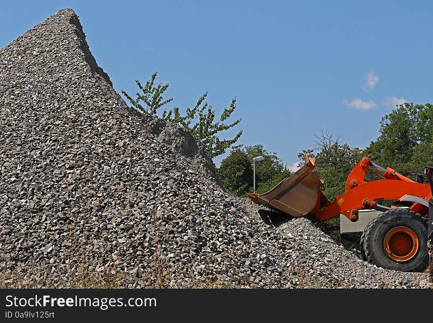 Excavator in front of a pile of rubble