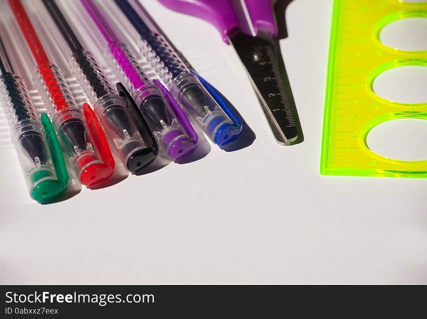 Colored pens, scissors and ruler closeup on light bacground