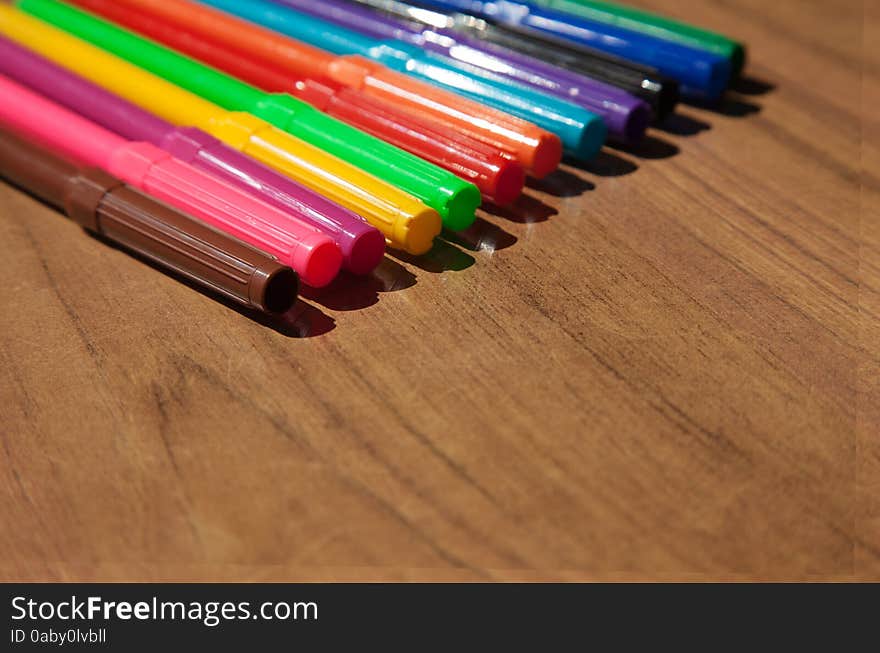 Colored markers on wooden table closeup