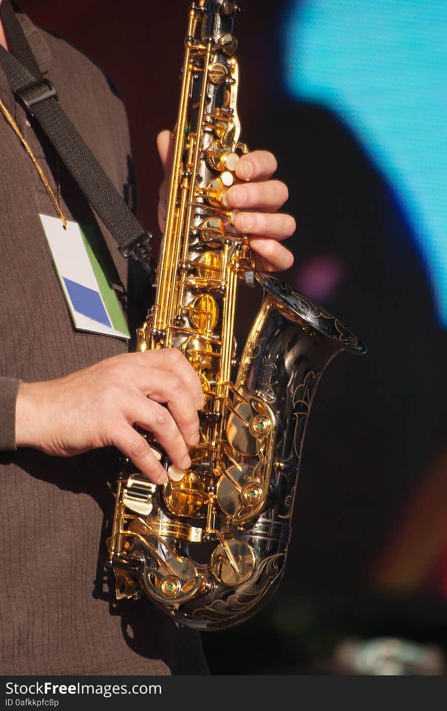 Hands of saxophonist in concert outside on summer day closeup