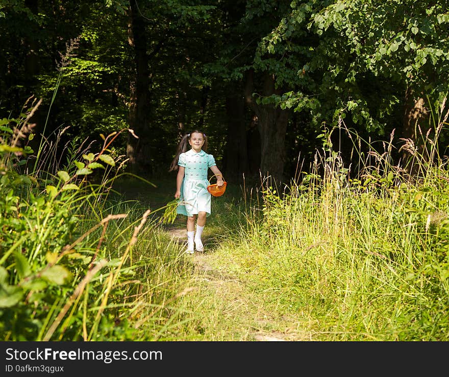 Little girl in green dress goes out of the forest on sunny summer day. Little girl in green dress goes out of the forest on sunny summer day