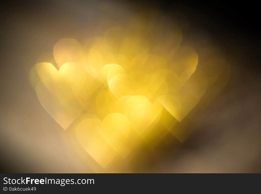 Festive background with defocused golden glitters, bokeh in a shape of a heart. Festive background with defocused golden glitters, bokeh in a shape of a heart.