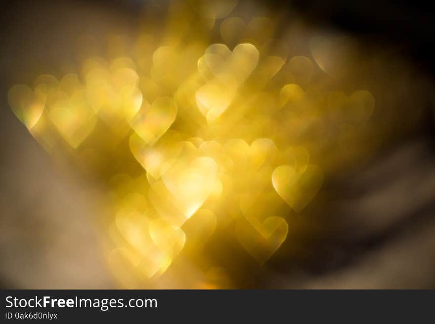 Festive background with defocused golden glitters, bokeh in a shape of a heart. Festive background with defocused golden glitters, bokeh in a shape of a heart.