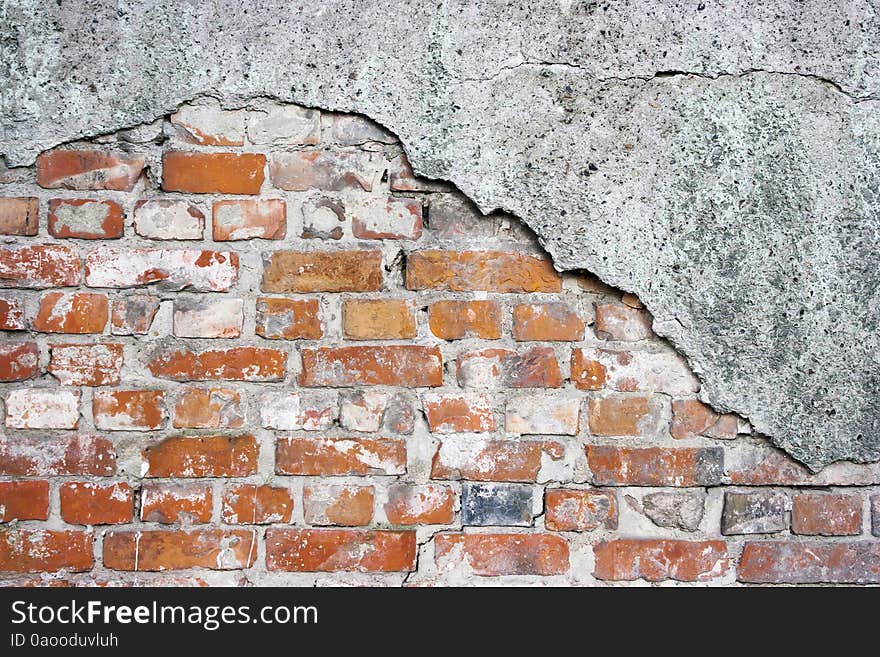 Old crumbling brick wall with cracked plaster